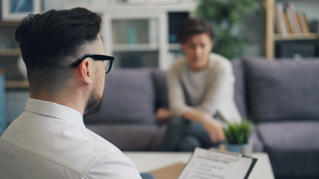 man sitting on a couch talking to a woman